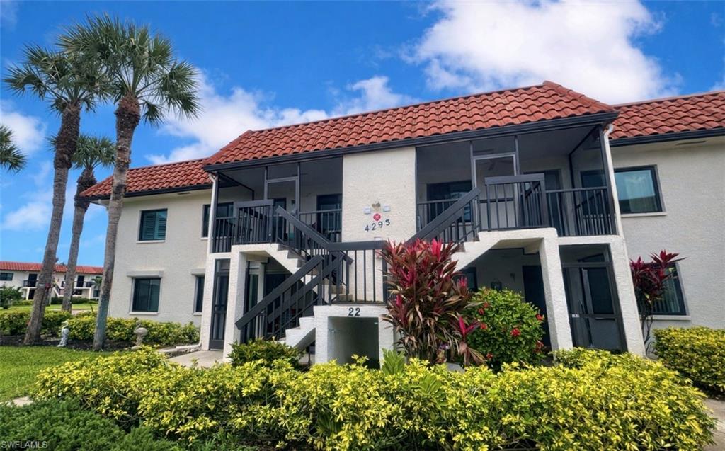 4293 27th Court Southwest, Unit 203 Naples, FL 34116 - Photo 2 of 22 a front view of a house with garden
