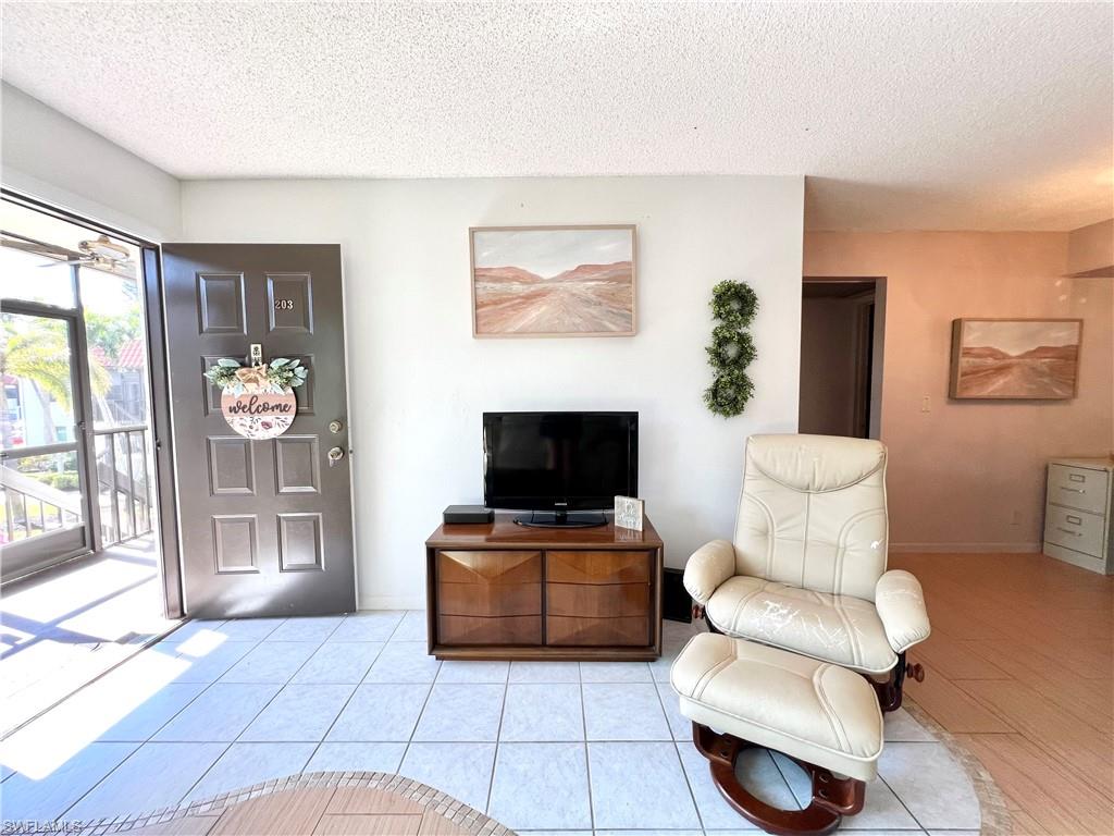 4293 27th Court Southwest, Unit 203 Naples, FL 34116 - Photo 7 of 26 a living room with furniture and a flat screen tv