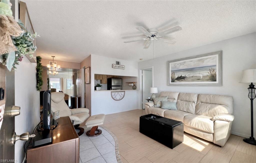 4293 27th Court Southwest, Unit 203 Naples, FL 34116 - Photo 8 of 22 a living room with furniture and a chandelier
