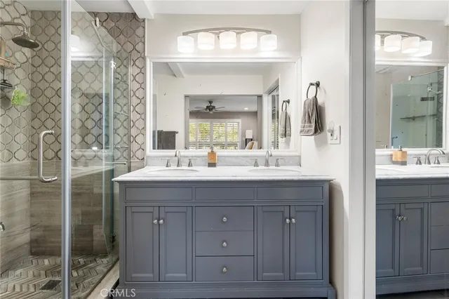 a bathroom with a granite countertop sink a mirror and a shower