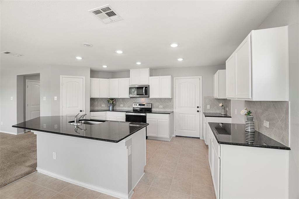 117 West Point Way Elgin, TX 78621 - Photo 2 of 21 Polished granite countertops complement white cabinetry and tile flooring in this functional culinary space.