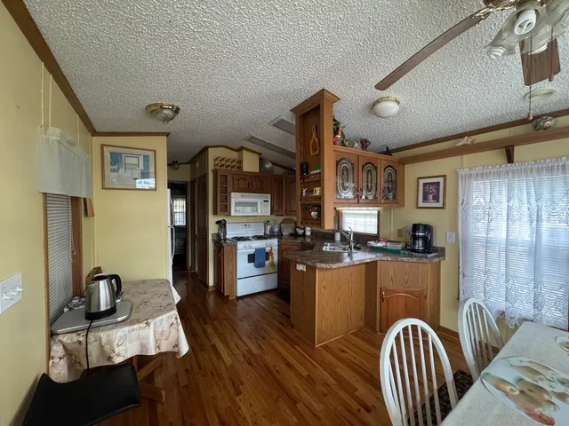 a kitchen with stainless steel appliances granite countertop a refrigerator a stove top oven a sink dishwasher and wooden cabinets with wooden floor