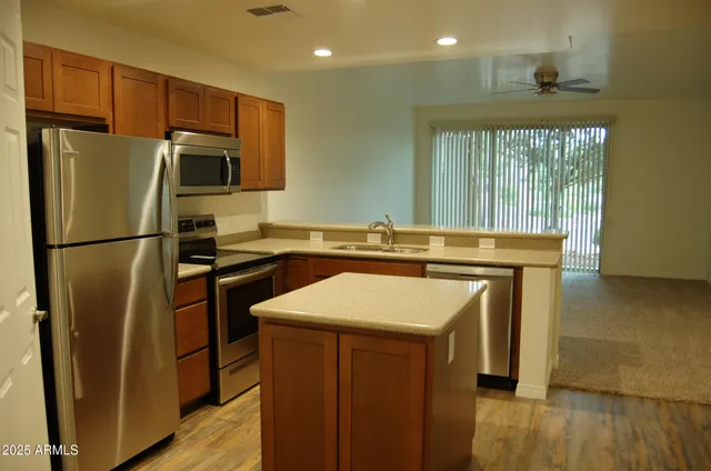 a kitchen with stainless steel appliances a refrigerator a sink a stove a microwave and island