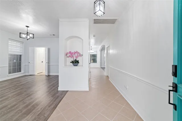 a view of a hallway with wooden floor and chandelier