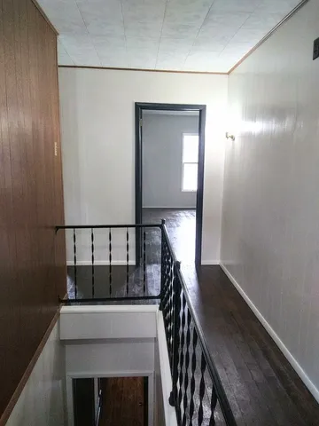 a view of a hallway with wooden floor and staircase