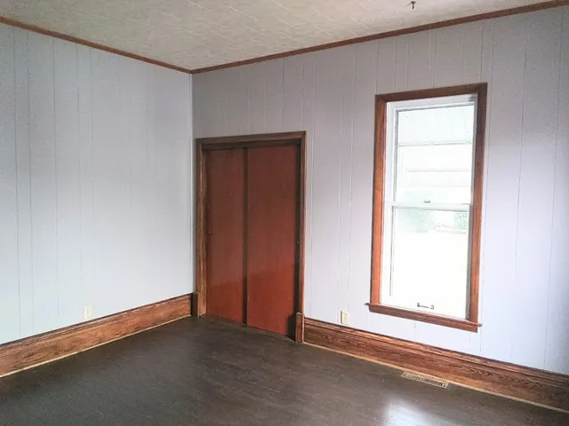 an empty room with wooden floor chandelier fan and windows