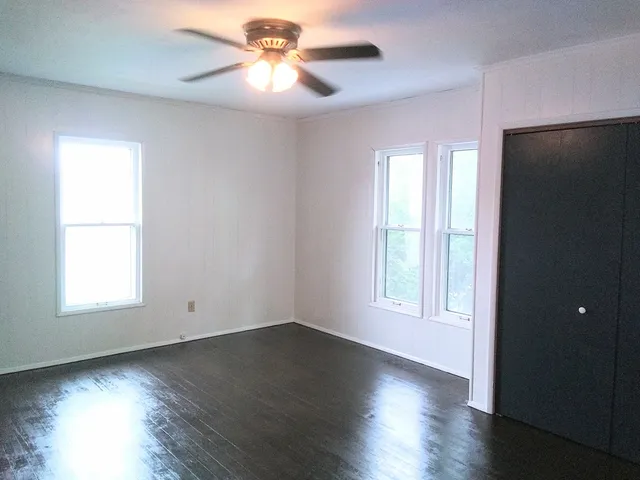 an empty room with wooden floor and windows