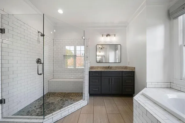 a bathroom with a granite countertop sink a toilet a mirror a bathtub and shower