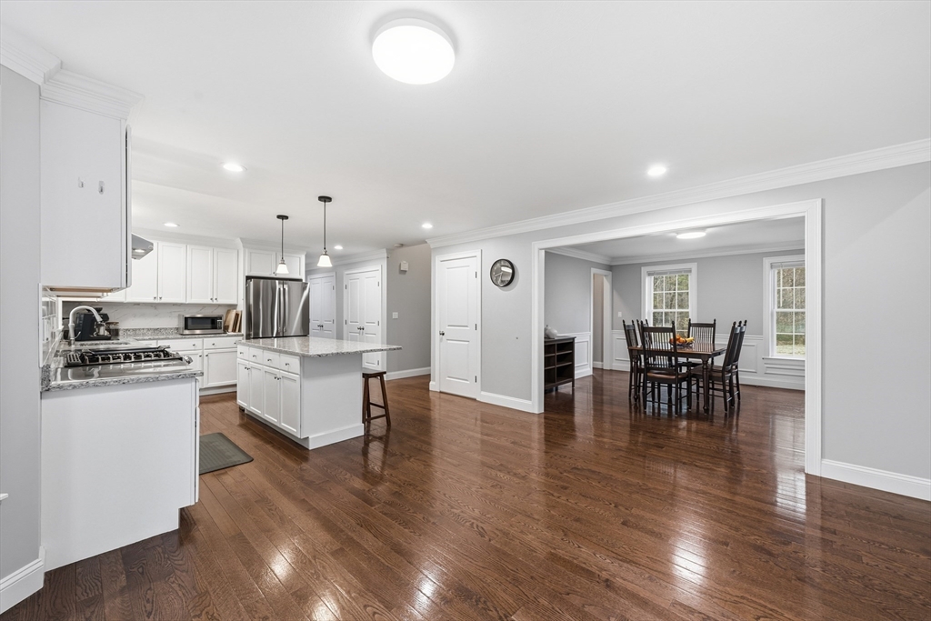 44 Bacon Street Pepperell, MA 01463 - Photo 10 of 42 a kitchen with stainless steel appliances granite countertop a stove top oven a sink a dining table and chairs with wooden floor