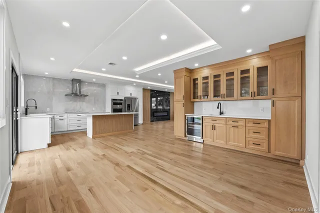 a large kitchen with stainless steel appliances granite countertop a large center island a stove a refrigerator white cabinets and wooden floor