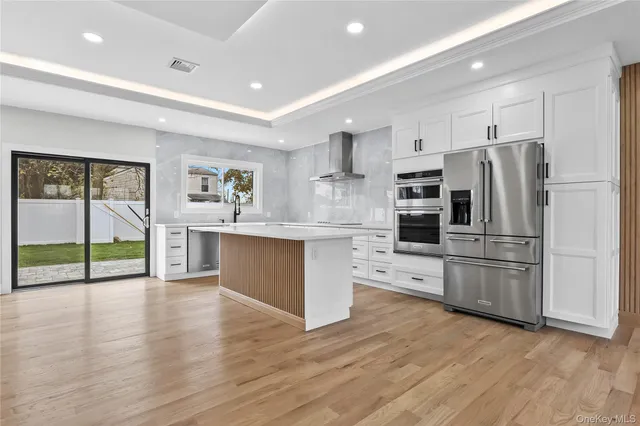 a kitchen with stainless steel appliances a refrigerator and wooden floors