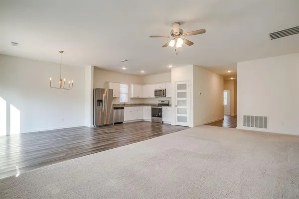 a view of a kitchen with a stove cabinets a ceiling fan and wooden floor