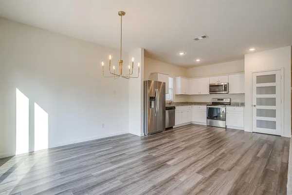 a view of kitchen with granite countertop stainless steel appliances refrigerator wooden floor dining table and chairs