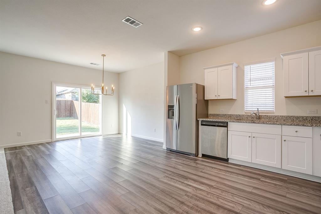 1405 Gentle Crk Lane Fort Worth, TX 76052 - Photo 23 of 40 a kitchen with stainless steel appliances granite countertop a refrigerator a sink dishwasher a stove with wooden floors and cabinets
