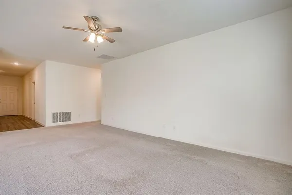 a view of an empty room with a chandelier fan