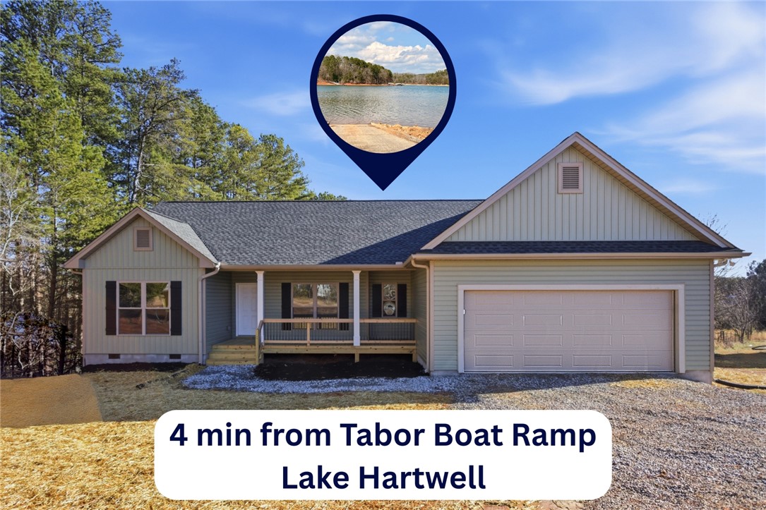 This charming home features a welcoming porch, an attached garage, and a lush, natural surroundings.