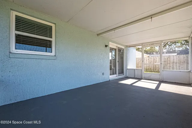 a view of empty room with floor to ceiling window and ceiling fan