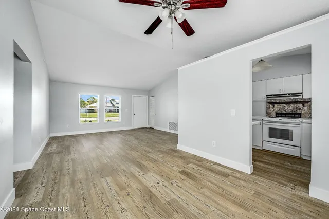 a view of empty room with wooden floor and window