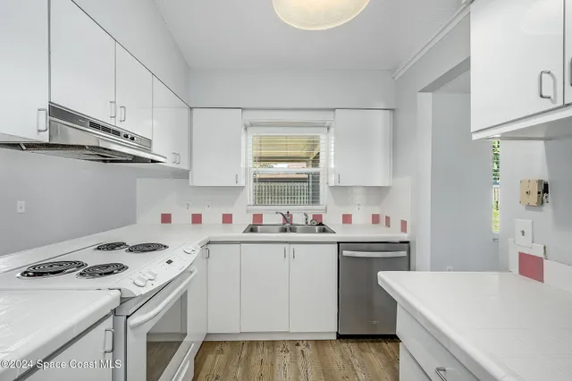 a kitchen that has a sink a stove and cabinets