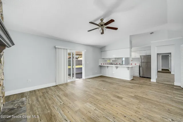 a view of an empty room with window and wooden floor