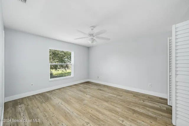 an empty room with a window and a ceiling fan