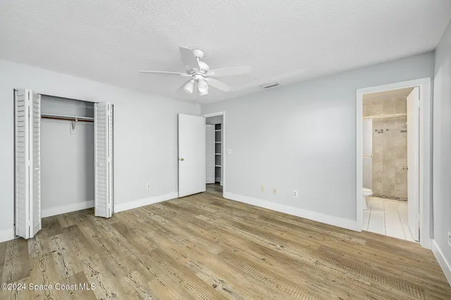 a view of empty room with wooden floor and ceiling fan