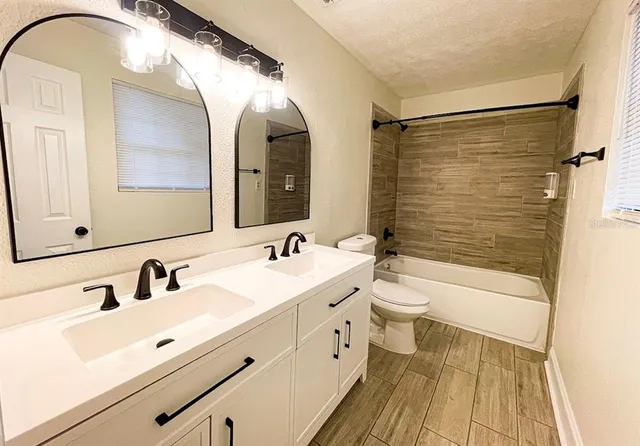 a bathroom with a double vanity sink mirror and bathtub