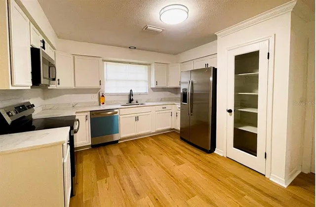 a kitchen with a sink a counter top space stainless steel appliances and cabinets