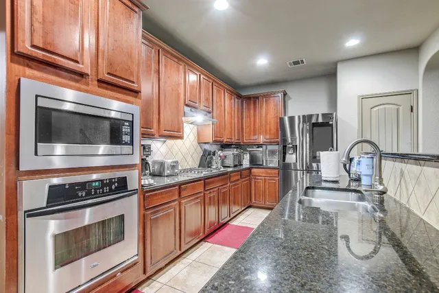 a kitchen with stainless steel appliances granite countertop a stove a sink and a microwave