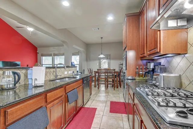a kitchen with stainless steel appliances granite countertop a stove a sink dishwasher and cabinets with wooden floor