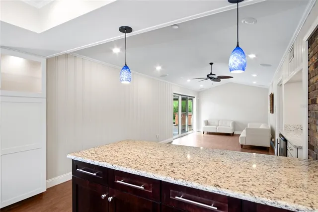 a room with kitchen island granite countertop cabinets and a chandelier