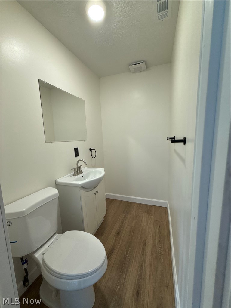 4841 Marigold Road Mentor, OH 44060 - Photo 9 of 12 Powder room featuring a white pedestal sink with cabinet storage, wood-finish flooring, and a wall-mounted mirror