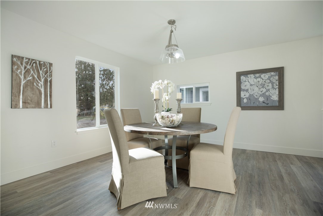 314 3rd Street Roy, WA 98580 - Photo 7 of 30 a dining room with wooden floor a chandelier a wooden table and chairs