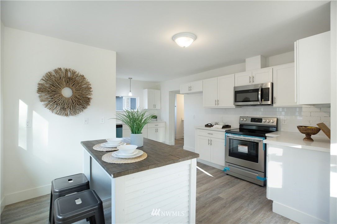 314 3rd Street Roy, WA 98580 - Photo 8 of 30 a kitchen with stainless steel appliances a stove a sink a microwave a refrigerator a stove and white cabinets with wooden floor