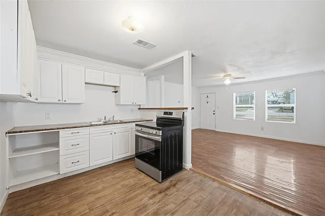 a kitchen with granite countertop a stove cabinets and wooden floor