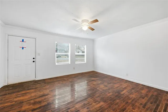 a view of an empty room with window and wooden floor