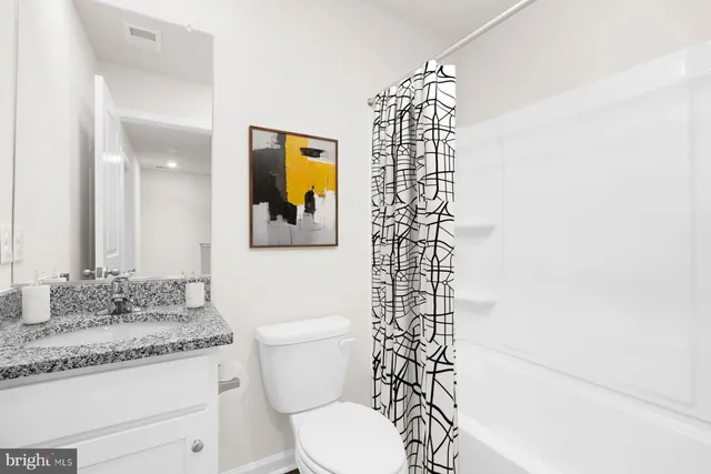 a bathroom with a granite countertop sink mirror vanity and toilet