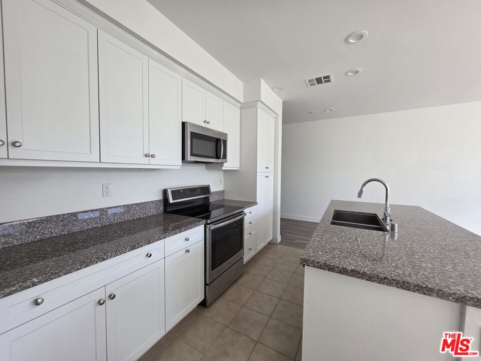 5308 Harvard Way Cypress, CA 90630 - Photo 6 of 17 a kitchen with granite countertop a sink a stove and cabinets