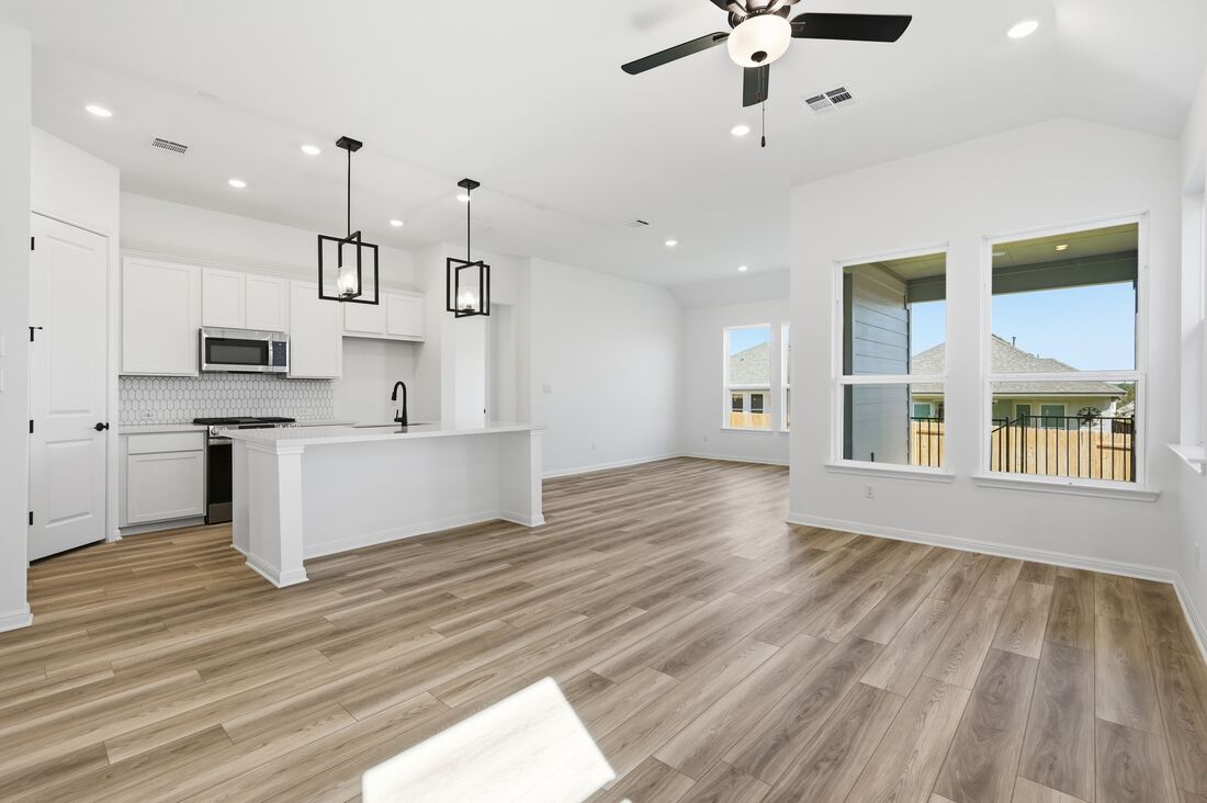 220 Wingstem Way Georgetown, TX 78633 - Photo 4 of 35 a large white kitchen with kitchen island a stove a sink dishwasher and a fireplace with wooden floor