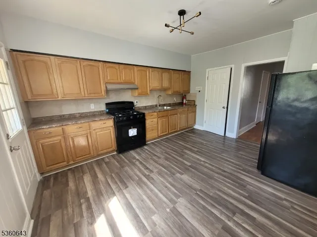 a kitchen with stainless steel appliances granite countertop a refrigerator a sink dishwasher a stove and white countertops with wooden floor