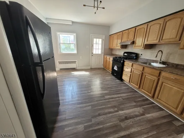 a kitchen with granite countertop a refrigerator a sink dishwasher a stove and white countertops with wooden floor