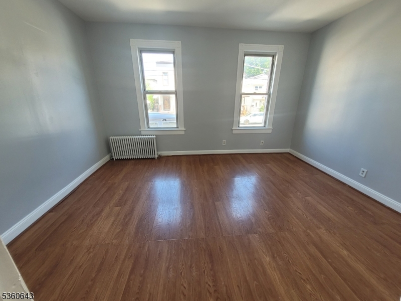 232 Niles Street Elizabeth, NJ 07202 - Photo 7 of 9 an empty room with wooden floor and windows