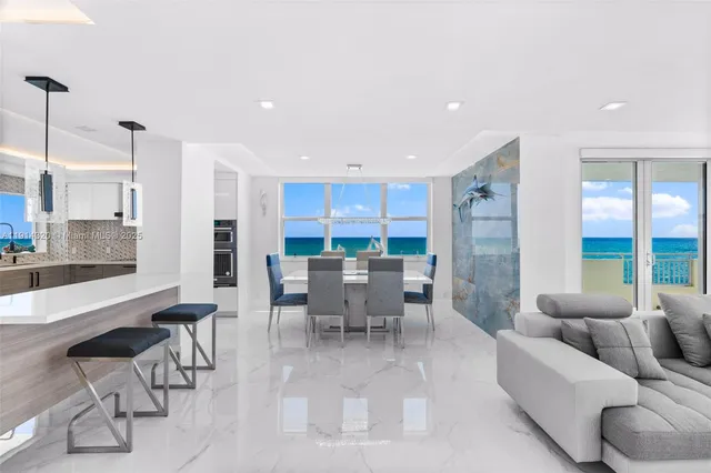 a large kitchen with stainless steel appliances a large counter top a couch and a view of living room