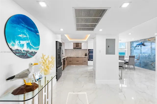 a large white kitchen with stainless steel appliances kitchen island granite countertop a refrigerator and a stove