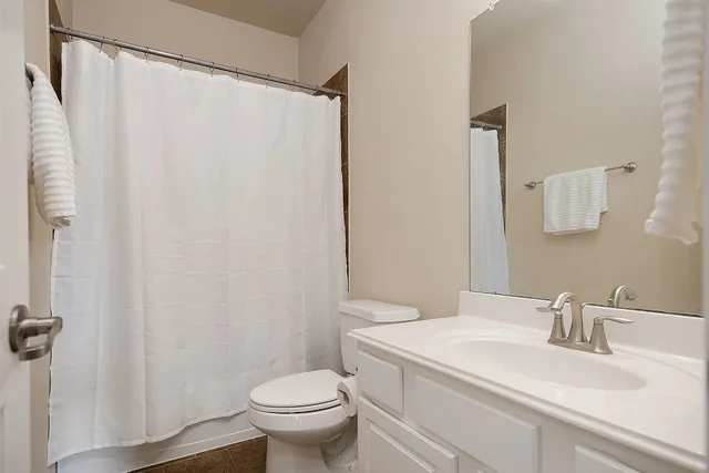 a bathroom with a granite countertop sink toilet and a mirror