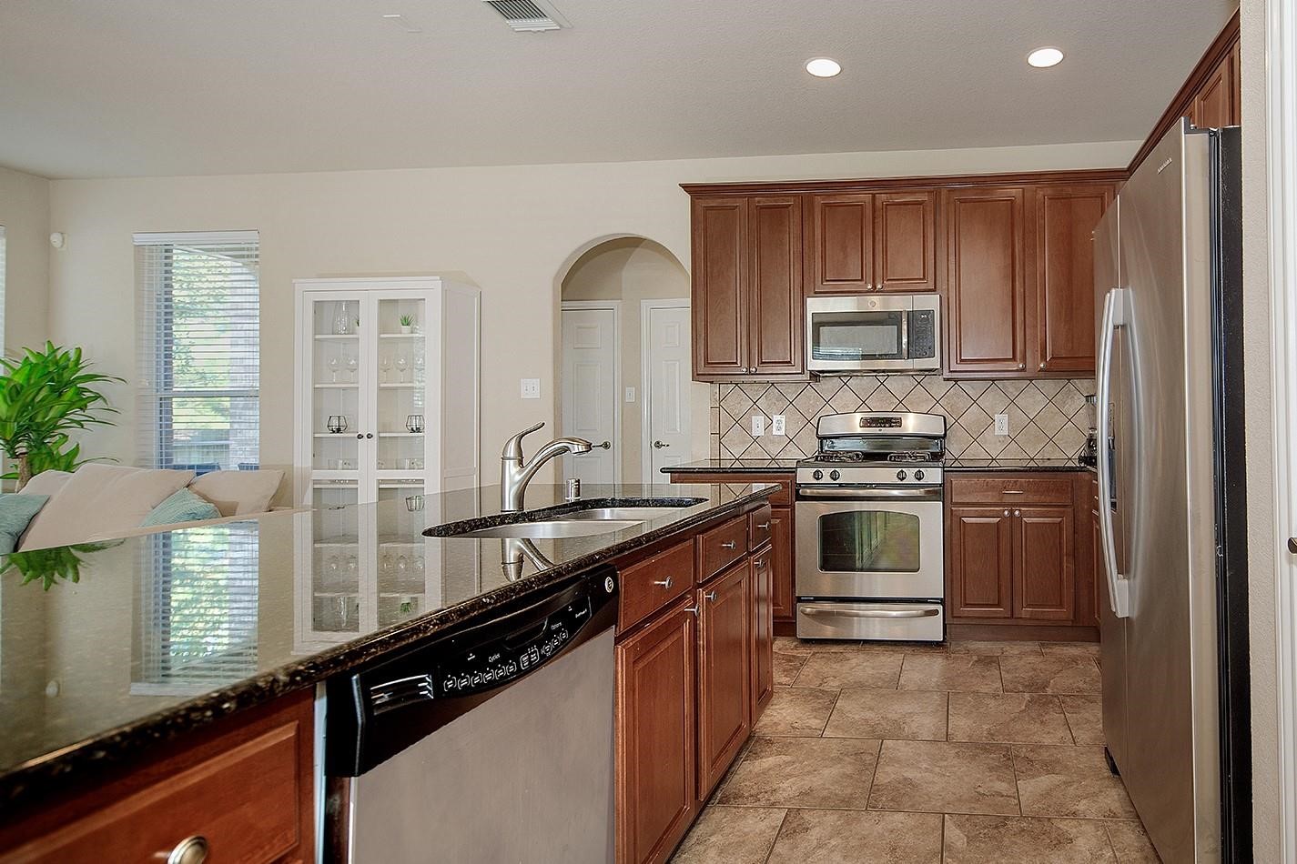 3 Pine Needle Place The Woodlands, TX 77382 - Photo 7 of 19 a kitchen with kitchen island granite countertop a stove sink and cabinets