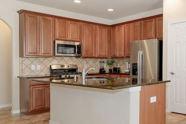 a kitchen with stainless steel appliances granite countertop a refrigerator stove top oven a sink and dishwasher