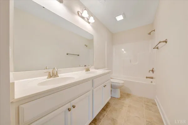 a spacious bathroom with a double vanity sink toilet mirror and bathtub