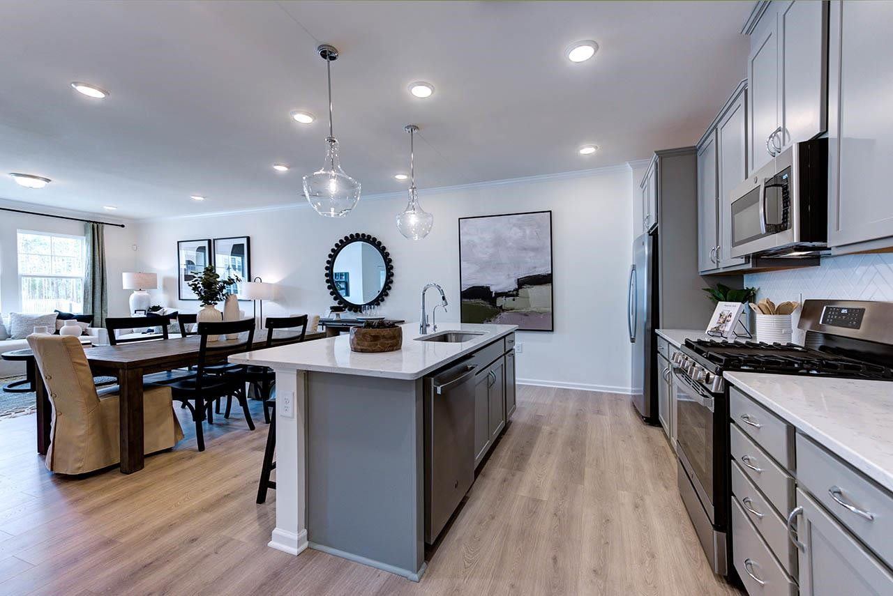 931 Baldwin Rdg Road Apex, NC 27523 - Photo 13 of 42 a kitchen with stainless steel appliances a stove top oven a sink dishwasher a dining table and chairs with wooden floor