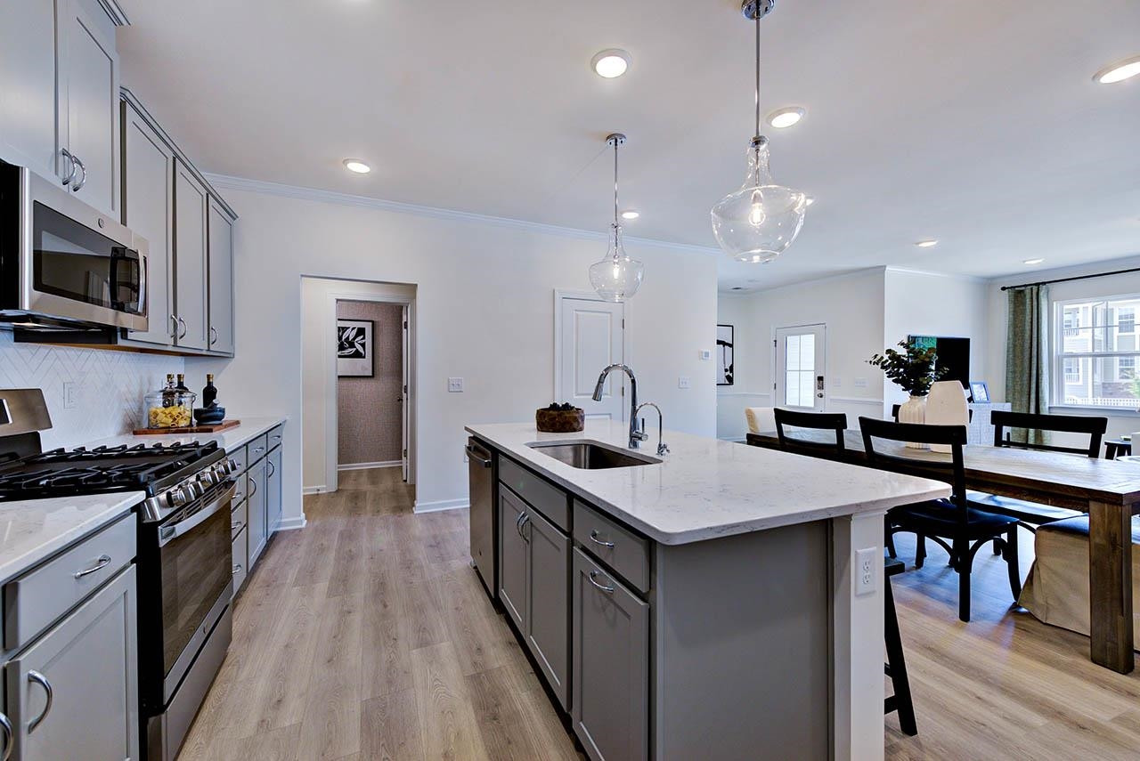 931 Baldwin Rdg Road Apex, NC 27523 - Photo 14 of 42 a kitchen with stainless steel appliances kitchen island granite countertop a stove top oven a sink dishwasher a dining table and chairs with wooden floor
